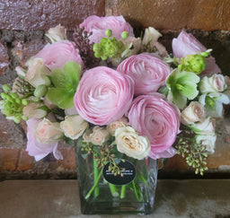 Arrangement with pink ranunculus spray roses eucalyptus and hellebores'