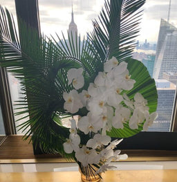 Arrangement with white orchids and sago palm leaves