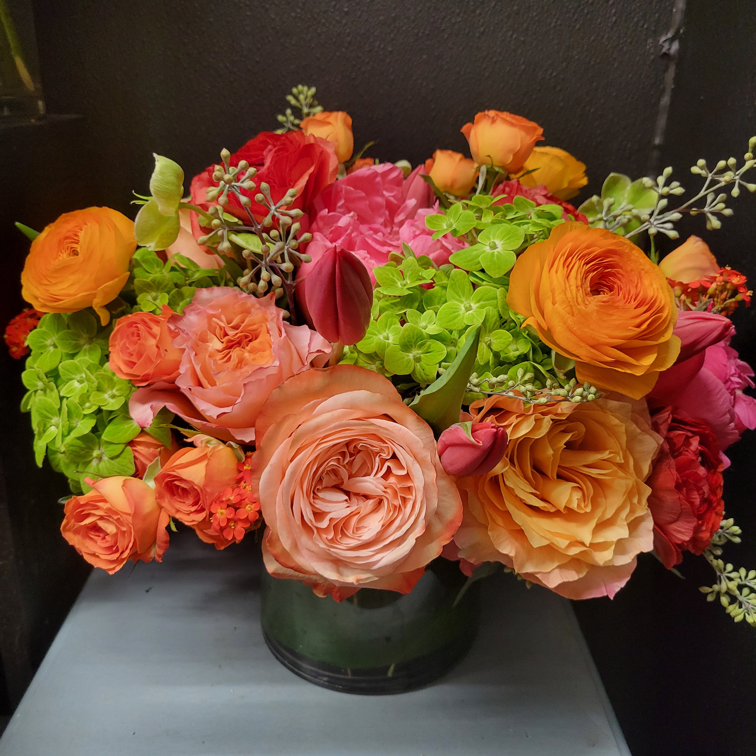 Arrangement with green hydrangea , garden roses , spray roses , ranunculus eucalyptus and hellebore.