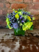 arrangement with blue thistle , green hydrangea grapes and moss