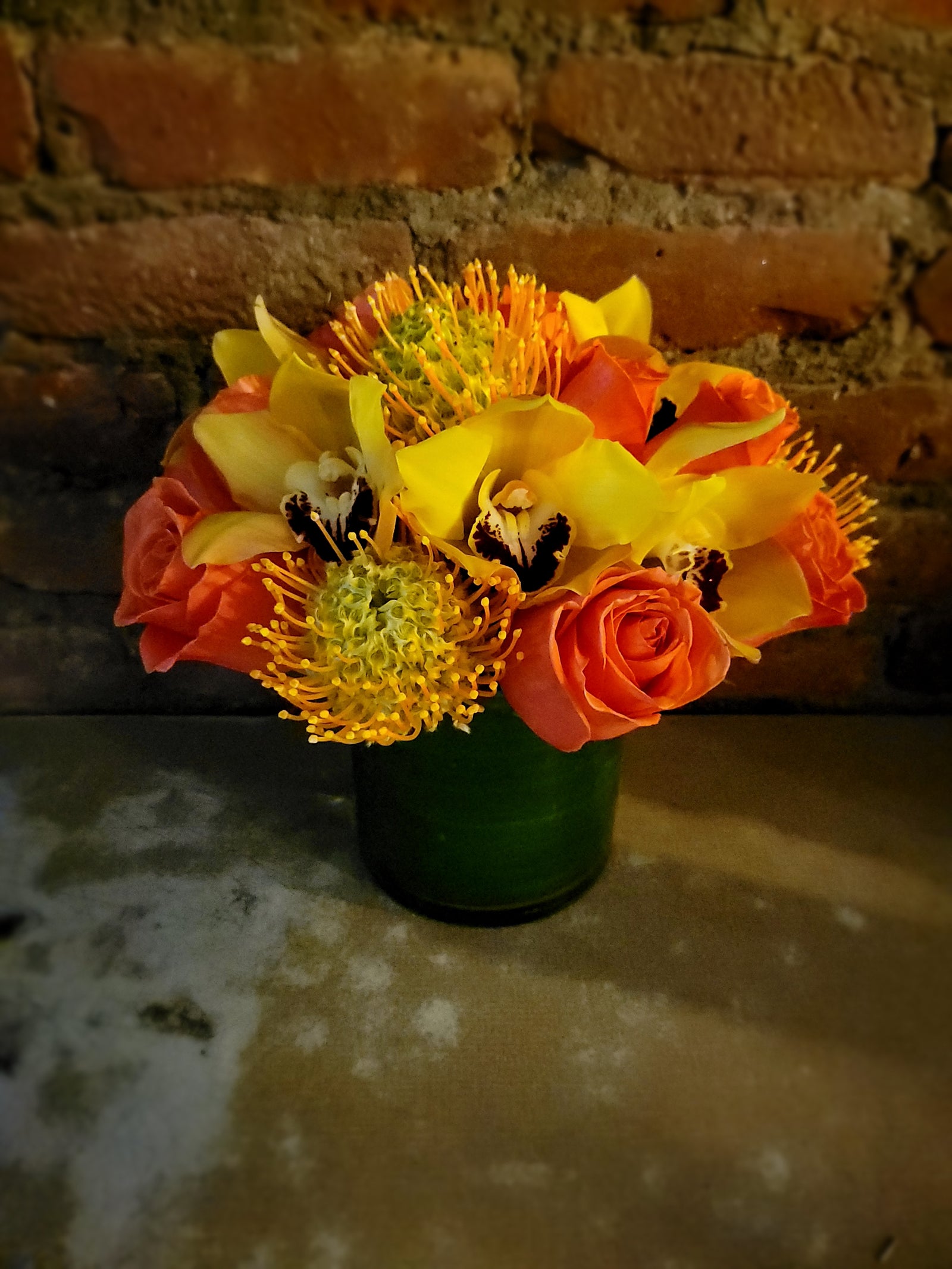 Glass vase with orchid orange roses and protea