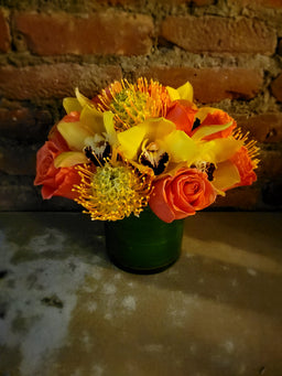 Glass vase with orchid orange roses and protea